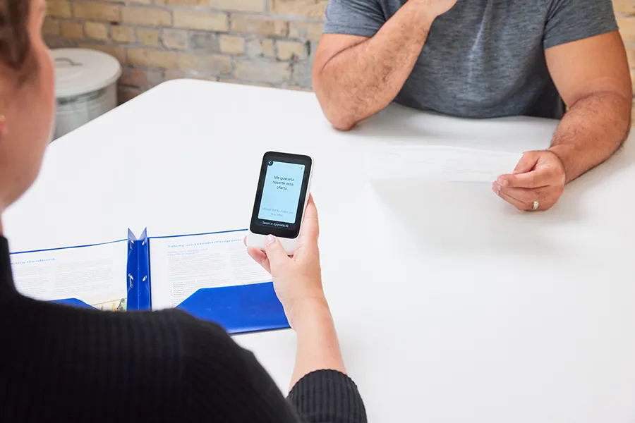 Two people at a desk using Pocketalk to communicate.